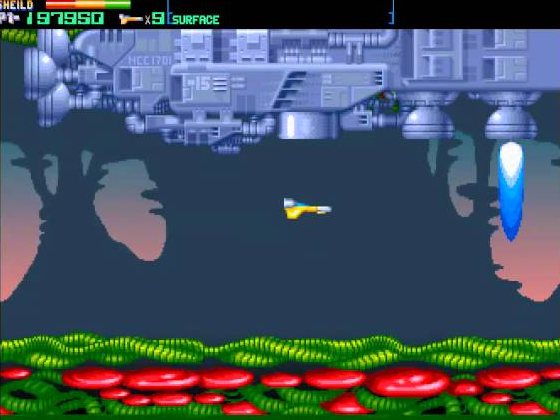 Overkill: a fighter skims under a huge alien mothership over a red alien landscape